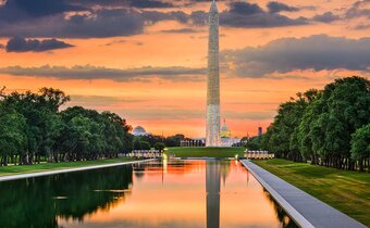 A warm sunset glows behind the Washington Monument and National Mall Reflecting Pool